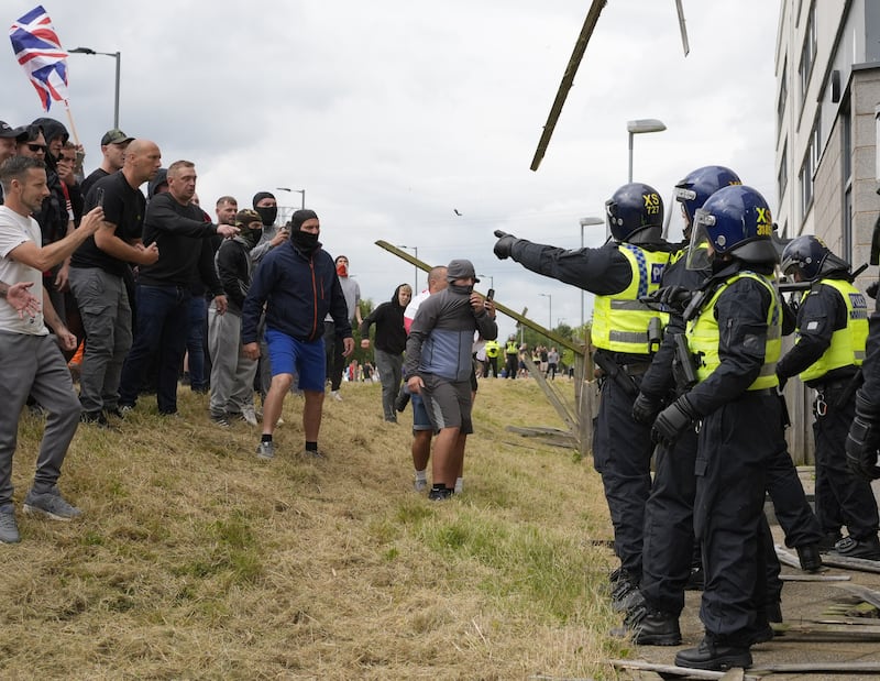 Ricky Hardman (left, bald head, black top and grey cargo trousers) was jailed for his part in the rioting outside a hotel housing asylum seekers in Rotherham