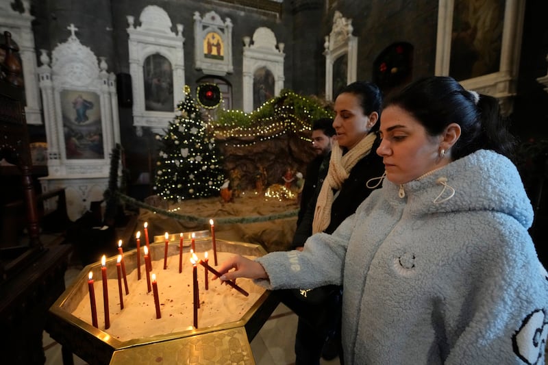 A Syrian Christian woman lights a candle during the first Sunday Mass since Bashar Assad’s fall, at Mariamiya Orthodox Church in old Damascus (Hussein Malla/AP)