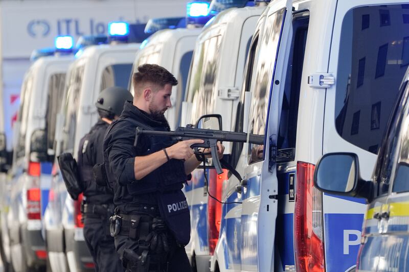 Police officers stand next to their vehicles after the incident in Munich (Matthias Schrader/AP)