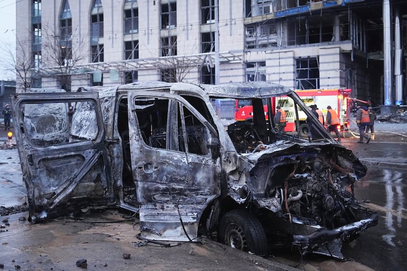 A destroyed car is seen as firefighters work on the site of a damaged building (Efrem Lukatsky/AP)