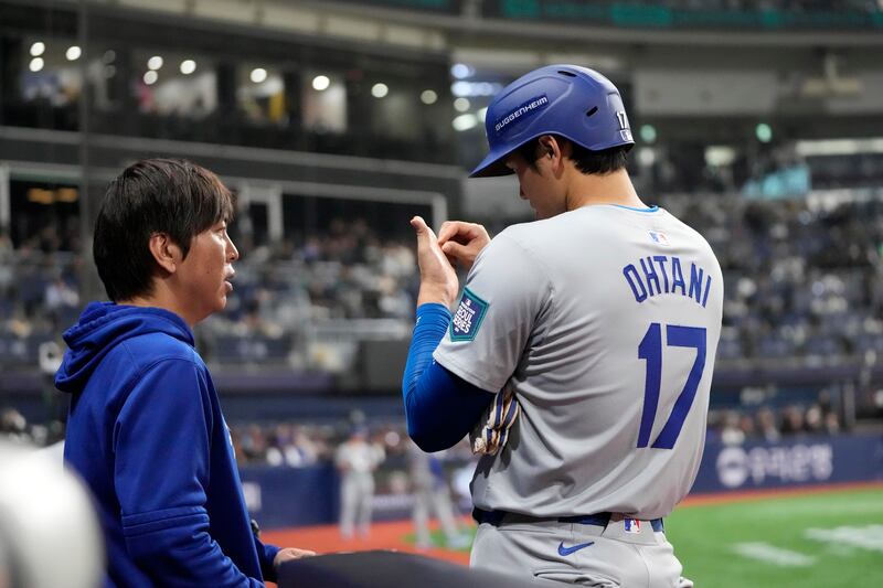 Los Angeles Dodgers designated hitter Shohei Ohtani, right, talks to his interpreter Ippei Mizuhara during an opening day baseball game against the San Diego Padres at the Gocheok Sky Dome in Seoul, South Korea (Lee Jin-man/AP)