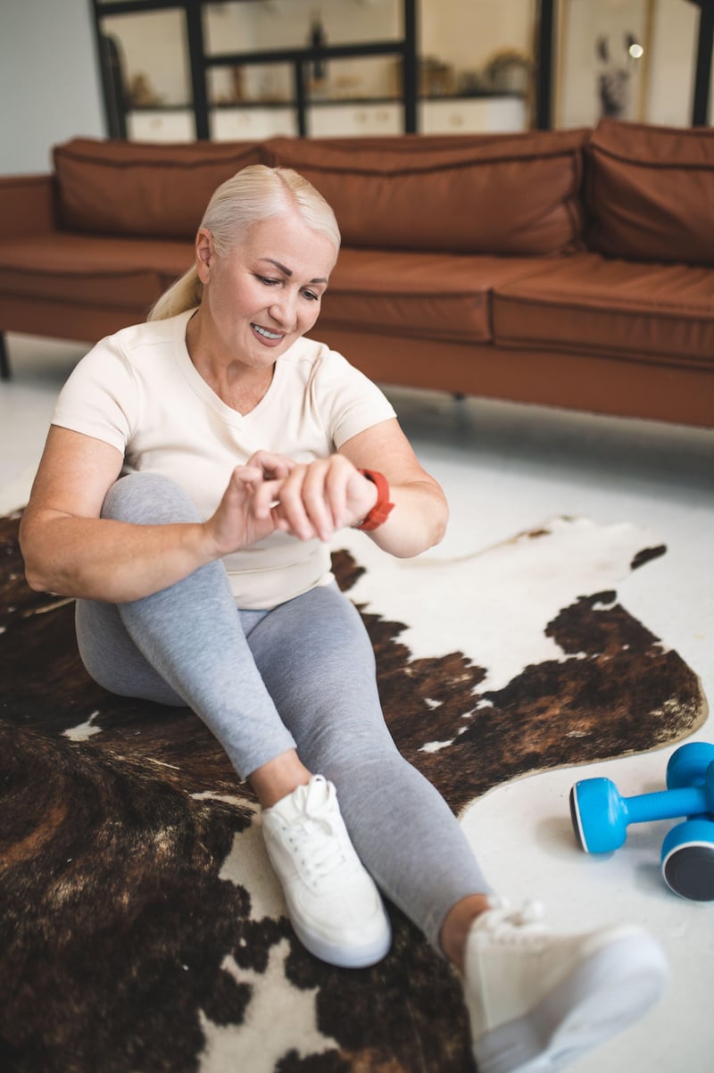 A woman checks her fitness tracker while exercising at home