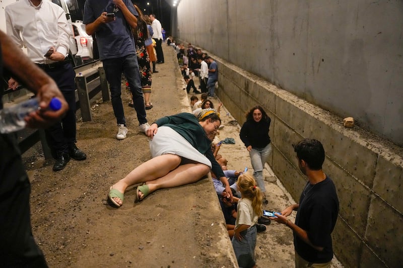 People take cover on the side of a road as a siren sounds in Shoresh, Israel (AP Photo/Ohad Zwigenberg)