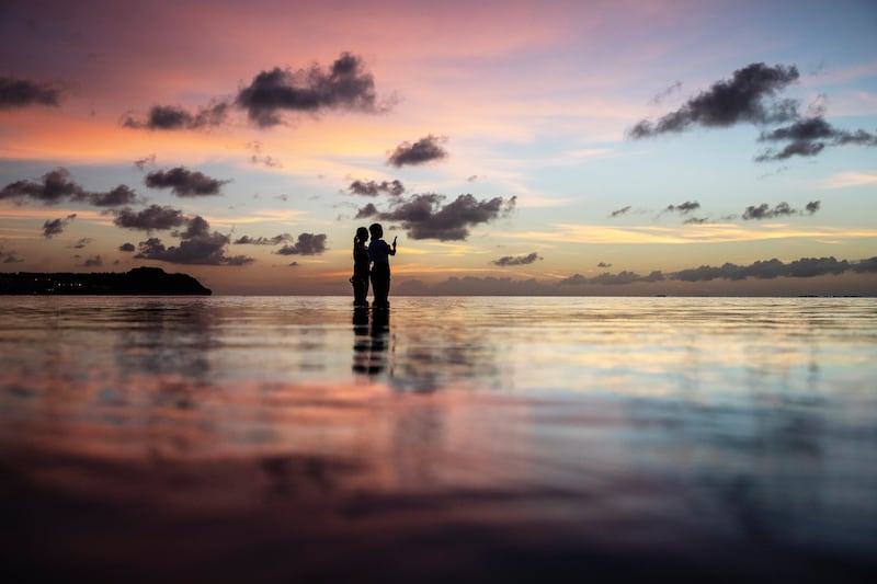 FILE – Tourists watch the sunset along a popular beach in Tamuning, Guam (David Goldman/AP)