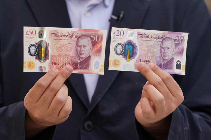 A person holds some of the newly released banknotes, featuring the King’s portrait, outside the Bank of England, London