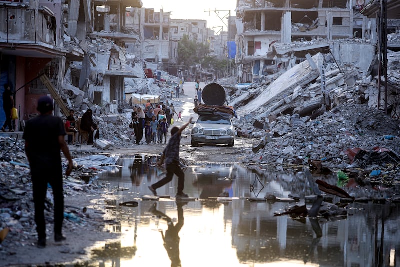 Palestinians displaced by the Israeli air and ground offensive on the Gaza Strip walk past sewage flowing into the streets