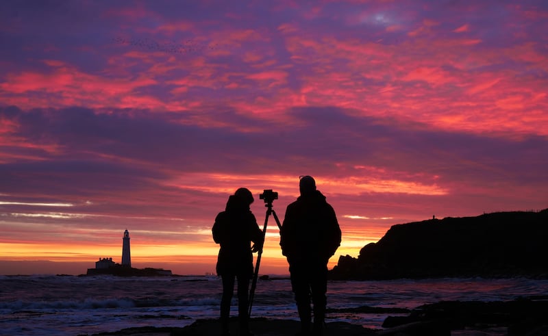 People takes photos of the colourful sky before sunrise at St Mary’s Lighthouse in Whitley Bay