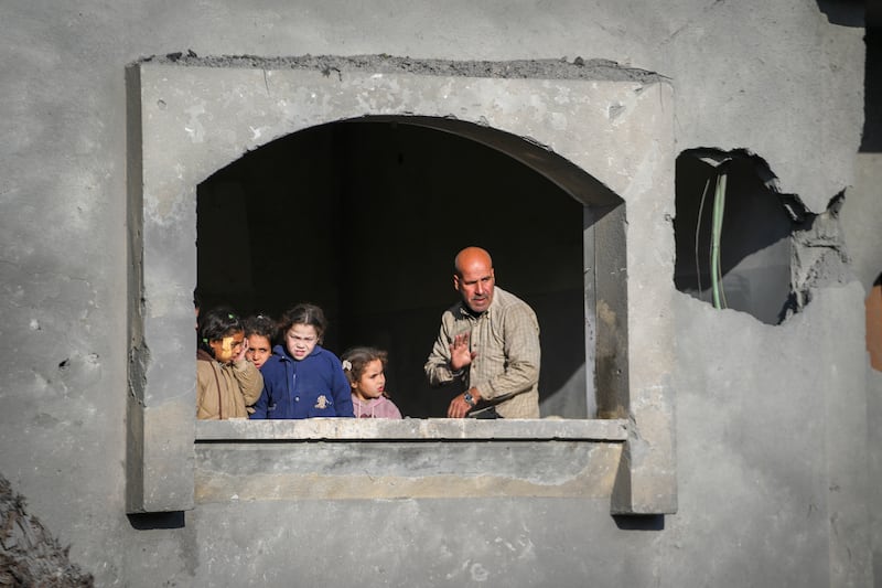 A man and a group of children watch the funeral procession for the victims of an Israeli strike on a home in Deir al-Balah (Abdel Kareem Hana/AP)