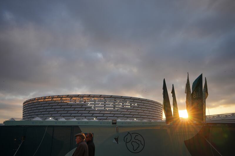 People walk with the Baku Olympic Stadium in the background during the the UN climate summit (Peter Dejong/AP)