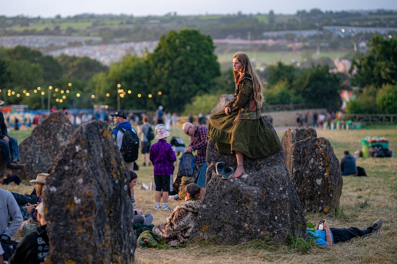 A person sits on the stone circle at the Glastonbury Festival