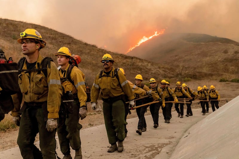 Fire crews walk as they battle the Kenneth Fire in the West Hills section of Los Angeles (Ethan Swope/AP)