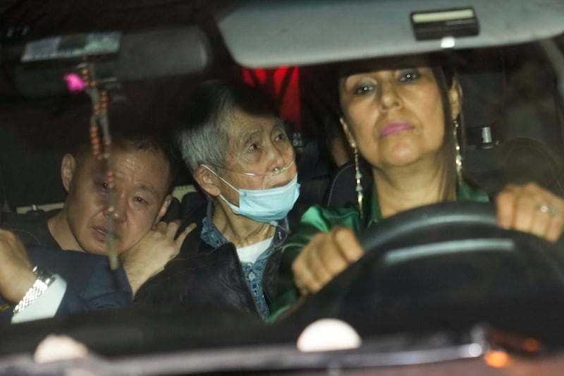 Peru’s former president Alberto Fujimori, centre, is driven out of prison by one of his lawyers, accompanied by his son Kenji, left, after his release in December 2023 (AP)