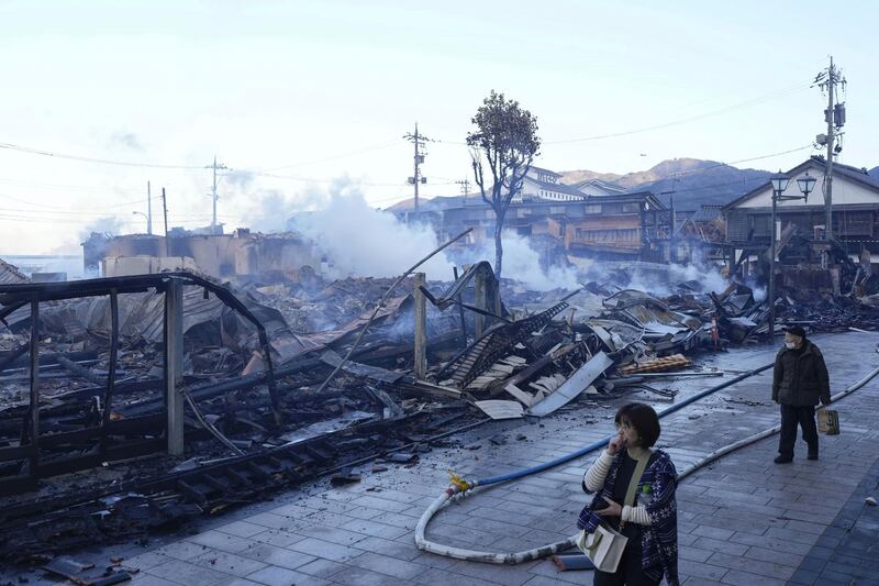 People walk past burn-out marketplace following earthquake in Wajima, Ishikawa prefecture, Japan (AP)