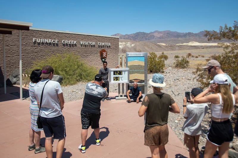 Tourists take photos in front of the Furnace Creek visitor centre thermometer (Daniel Jacobi II/Las Vegas Review-Journal via AP)