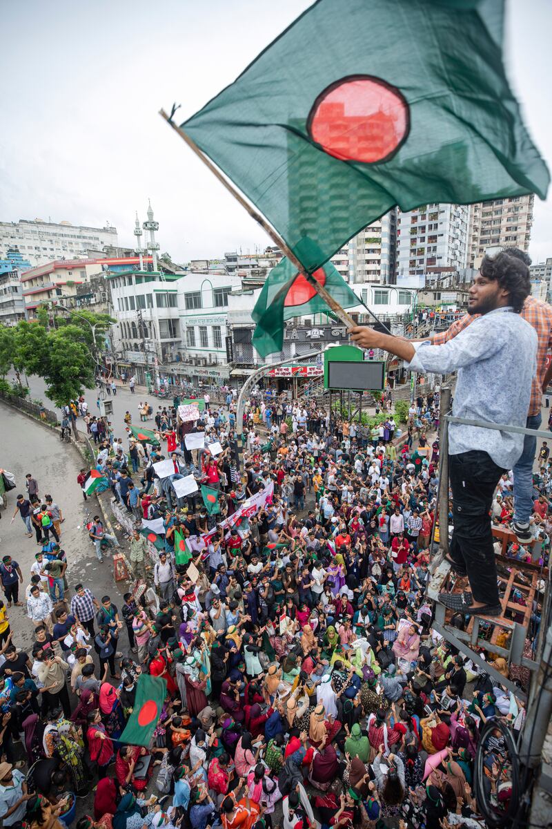 An activist waves a Bangladesh flag during a protest march (Rajib Dhar/AP)