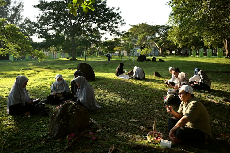 People pray at a mass grave of victims of the tsunami in Banda Aceh, Indonesia (Reza Saifullah/AP)