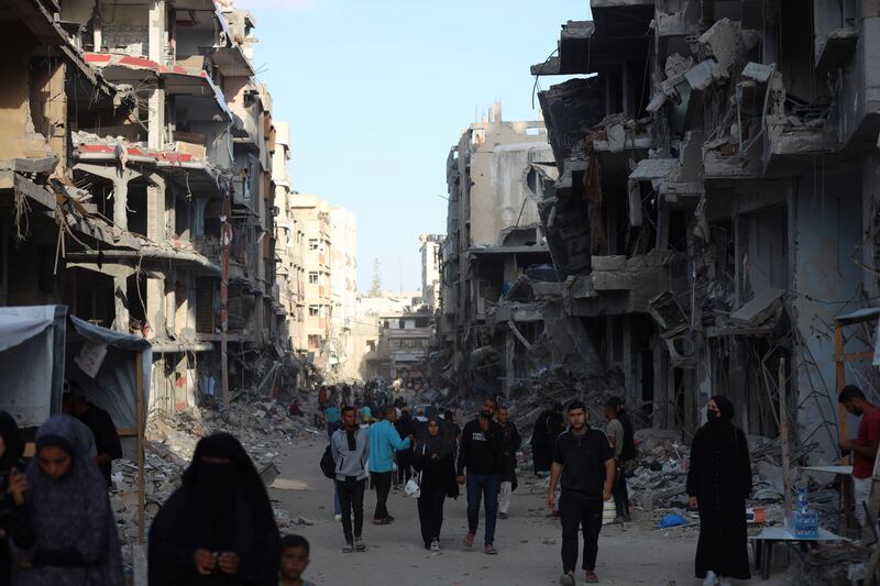 Palestinians walk through the debris after an Israeli air and ground offensive in Khan Younis (Saher Alghorra/AP)