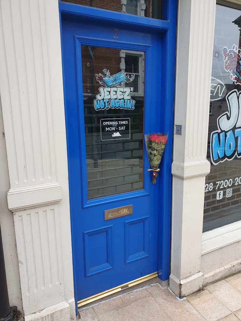 A single bunch of red roses, a poignant floral tribute, left at Noah Karran’s mobile phone repair shop in Derry city centre.