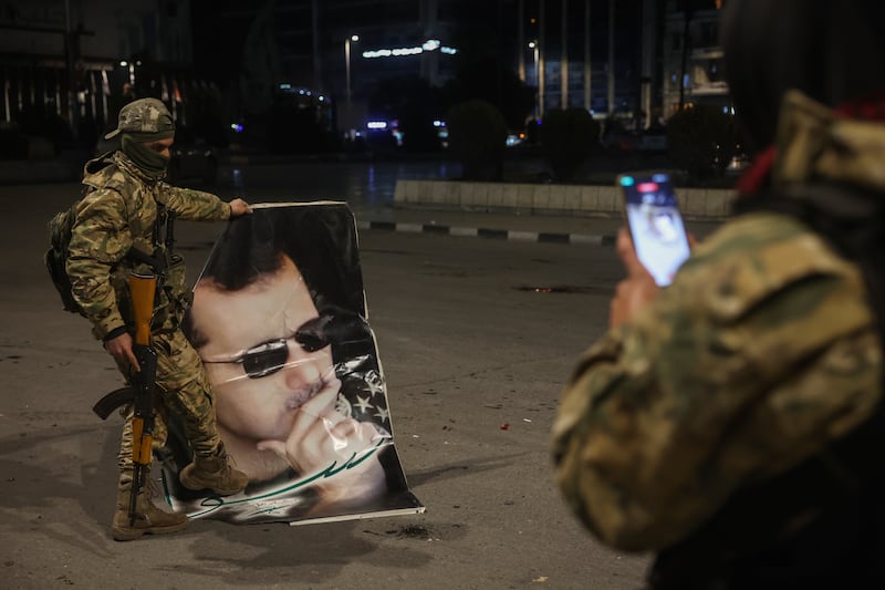 A Syrian opposition fighter takes a picture of a comrade stepping on a portrait of Syrian president Bashar Assad in Aleppo (AP Photo/Ghaith Alsayed)