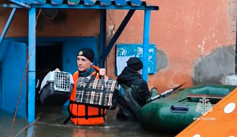 An emergency worker carries belongings of evacuated residents (Russian Emergency Ministry Press Service/AP)