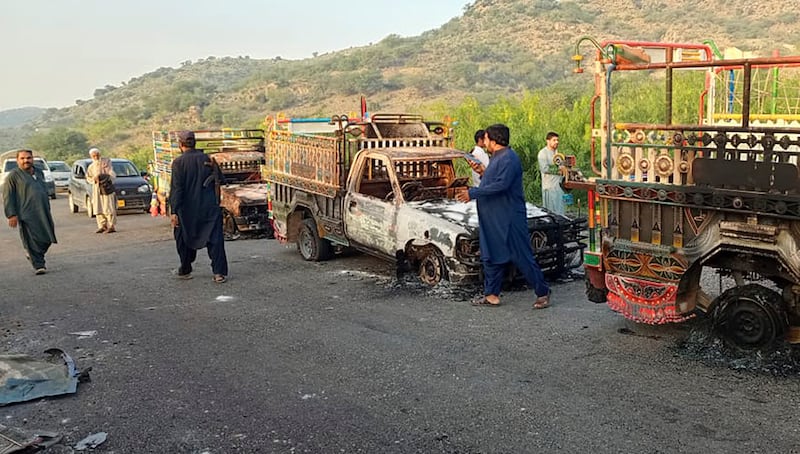 People look at burnt vehicles, torched by gunmen after killing passengers, on a highway in Musakhail, in Pakistan’s volatile Baluchistan province (Rahmat Khan/AP)