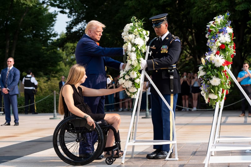 Former US Marine Corps corporal Kelsee Lainhart left, and Mr Trump place a wreath in honour of the 13 service members killed at Abbey Gate (Alex Brandon/AP)