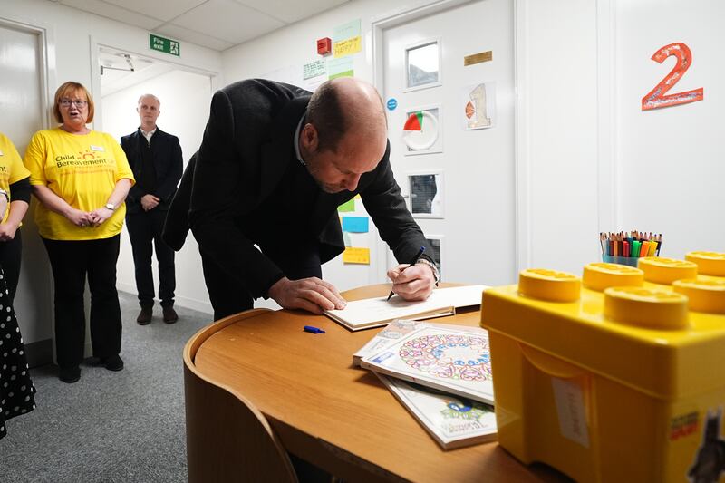 William signs the visitors’ book during a visit to the charity service in Widnes