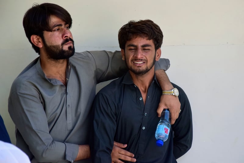 A man comforts another over the death of a family member killed by gunmen in Musakhail (Arshad Butt/AP)