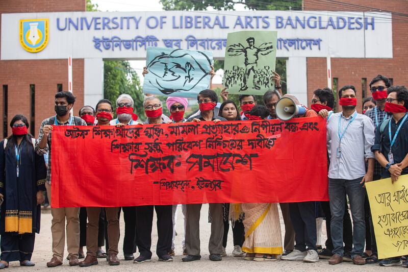 University teachers wear red masks as they demand justice for the victims killed in the recent countrywide deadly clashes during a protest in Dhaka, Bangladesh, on Wednesday (Rajib Dhar/AP)