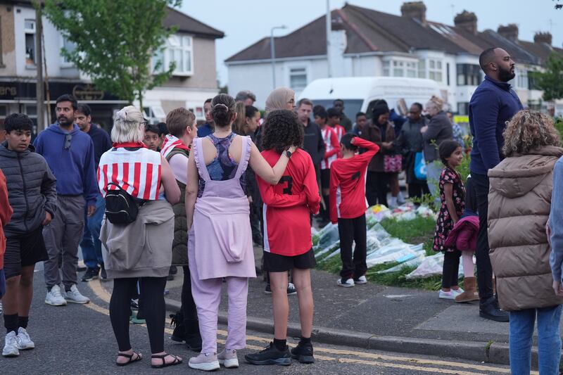 Members of the community look at floral tributes in Hainault