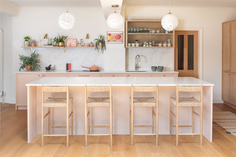 A soft-hued plaster pink kitchen pairs with oak veneered cabinets to create a calming, sanctuary-like space