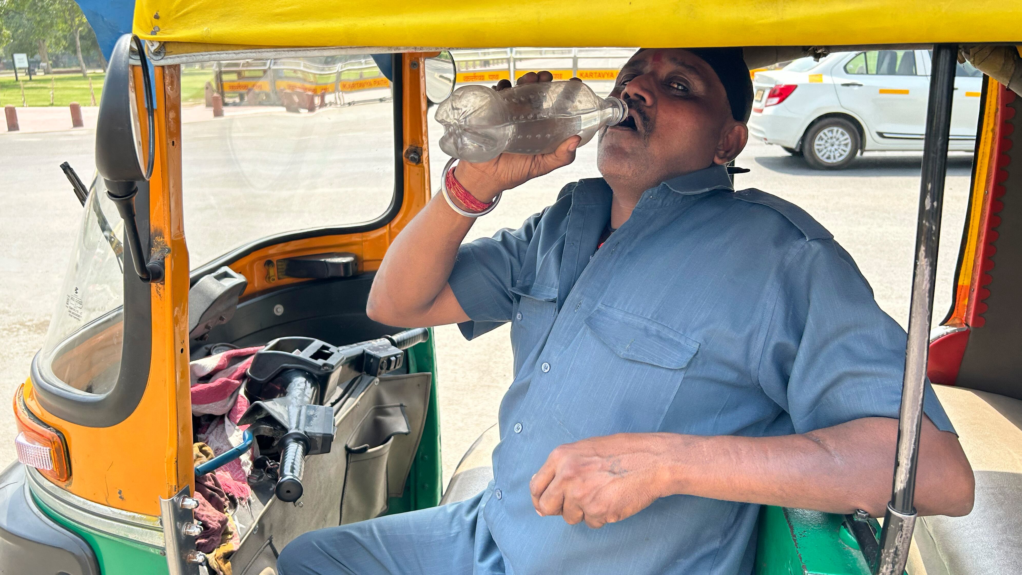 An auto-rickshaw driver drinks water as he takes a break in New Delhi, India (AP Photo/Shonal Ganguly)