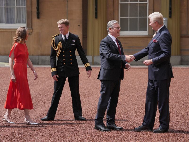 Sir Clive Alderton, right, and Royal Navy Commander William Thornton, in uniform, welcome Sir Keir Starmer and his wife Lady Starmer to the palace