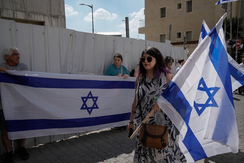 Mourners wave Israeli flags as they accompany the family of Israeli-American hostage Hersh Goldberg-Polin, who was killed in Hamas captivity in the Gaza Strip, on their way to his funeral in Jerusalem (Leo Correa/AP)