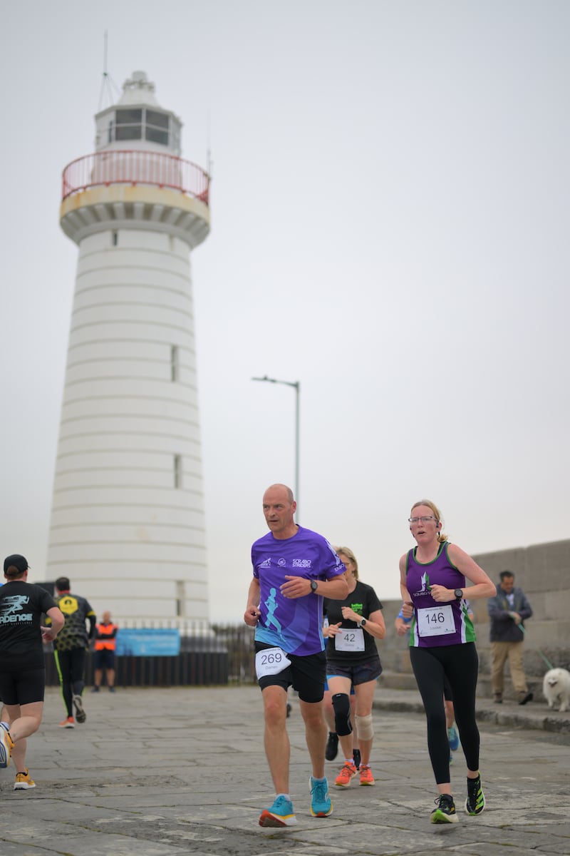 Group of runners in 5k race in front of white lighthouse