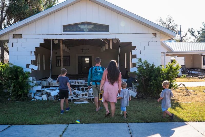 A family check a damaged church in the aftermath of Hurricane Helene in Horseshoe Beach, Florida (AP Photo/Gerald Herbert)