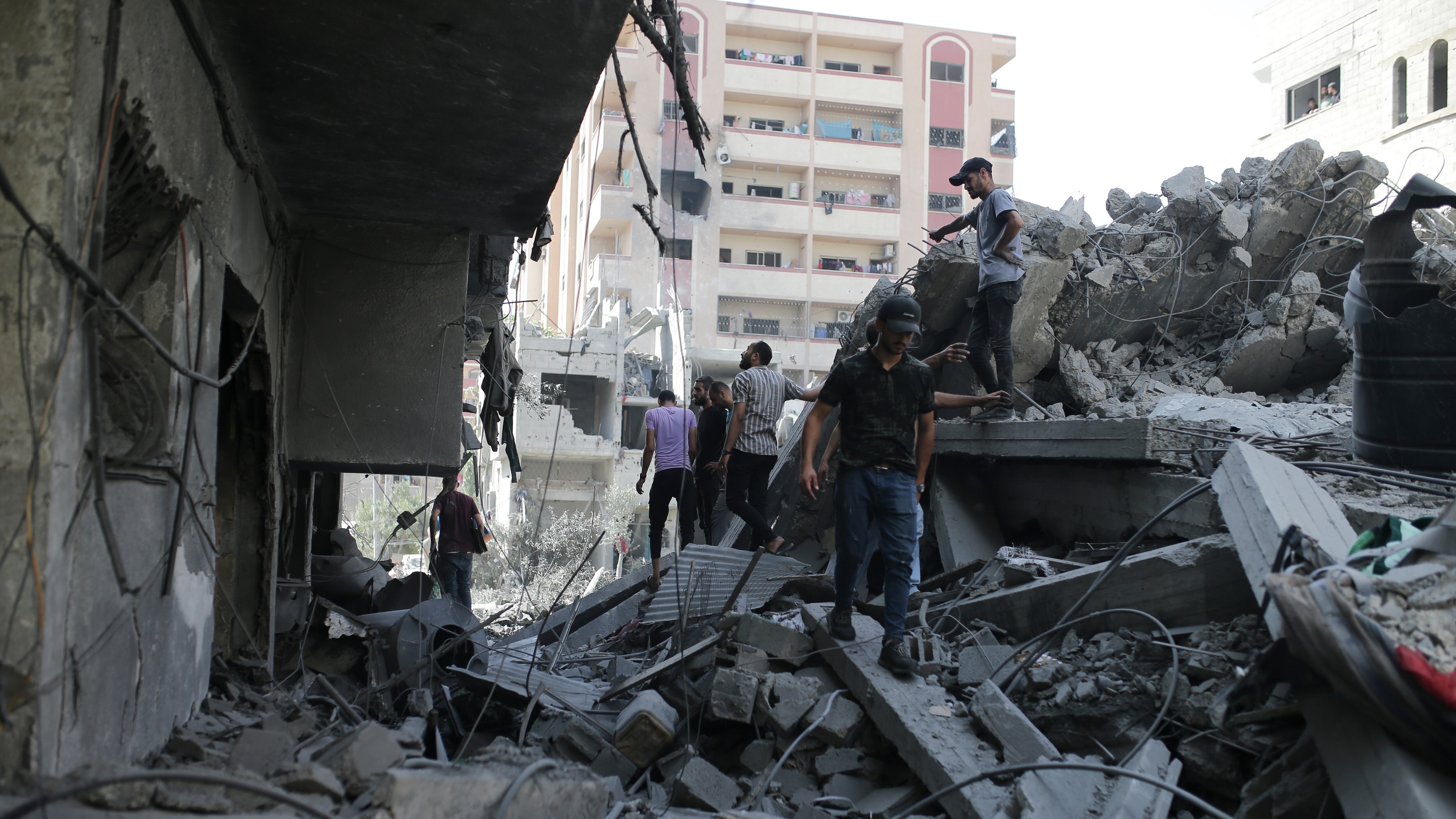Palestinians stand on the rubble of a building bombed by Israel in the Nuseirat refugee camp, Gaza Strip (Jehad Alshrafi/AP)