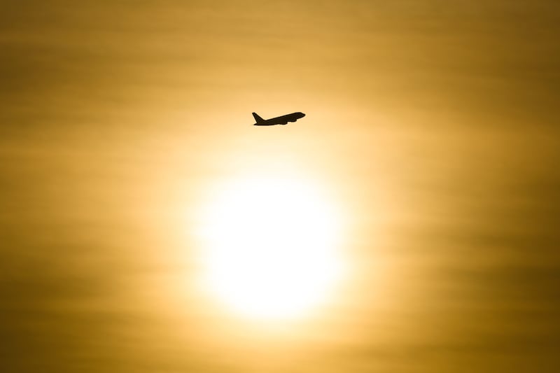 An airplane soars through a golden sky, silhouetted against the radiant glow of the setting sun in Belfast. PICTURE: MAL MCCANN