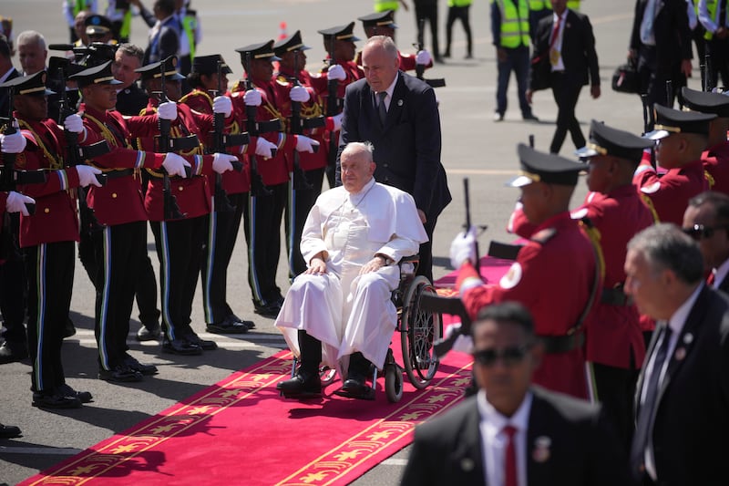 Pope Francis, in his wheelchair, is welcomed by members of the honour guard at Dili Presidente Nicolau Lobato International Airport in Dili, East Timor (Dita Alangkara/AP)