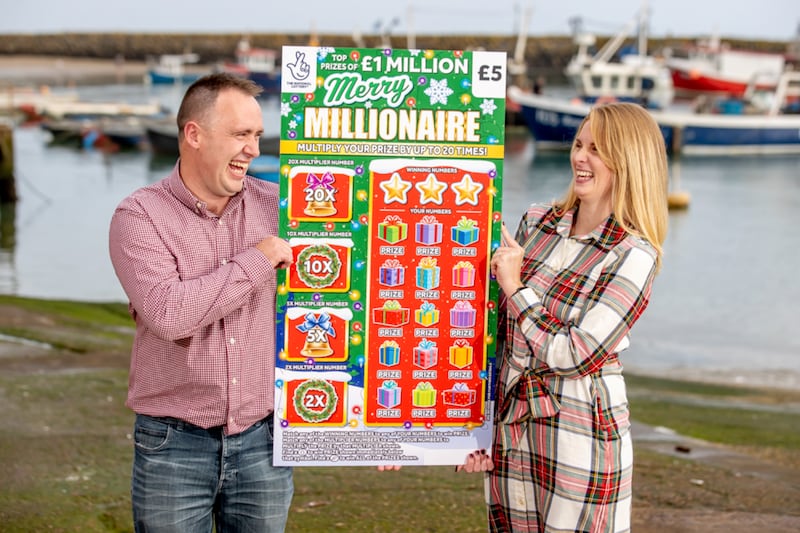 Couple hold a giant scratch card which they won £1 million from