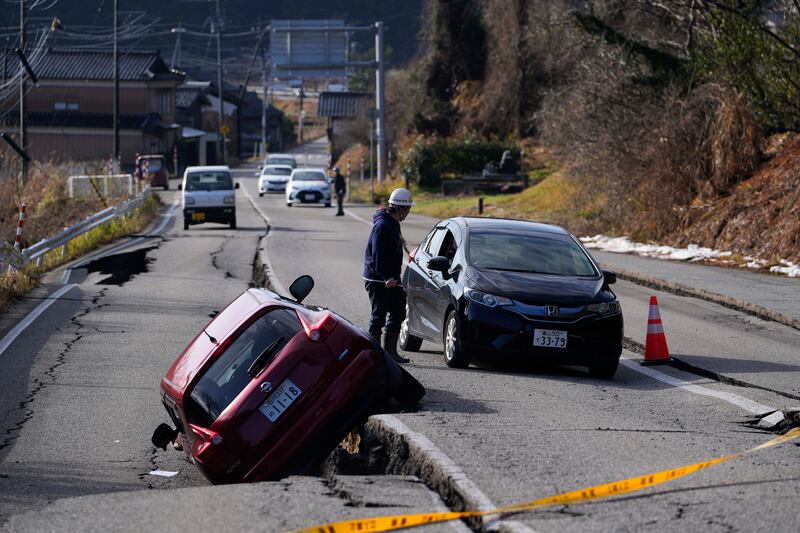 A man directs a driver moving through a damaged street near Anamizu town in the Noto peninsula facing the Sea of Japan (Hiro Komae/AP)