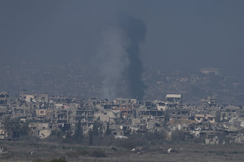 Smoke rises in Gaza behind buildings destroyed by Israeli bombardments on Thursday (Tsafrir Abayov/AP)