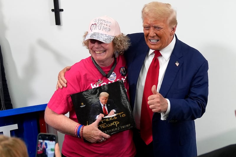 Donald Trump, right, poses with a supporter during a stop at a campaign office (Carolyn Kaster/AP)