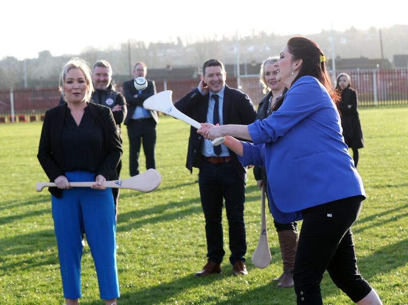 Emma Little-Pengelly has a go at hurling alongside Michelle O'Neill at St Paul's GAC in west Belfast.