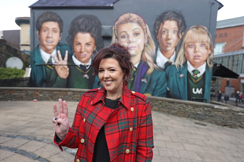 Derry Girls writer Lisa McGee in front of a Derry Girls mural in Derry