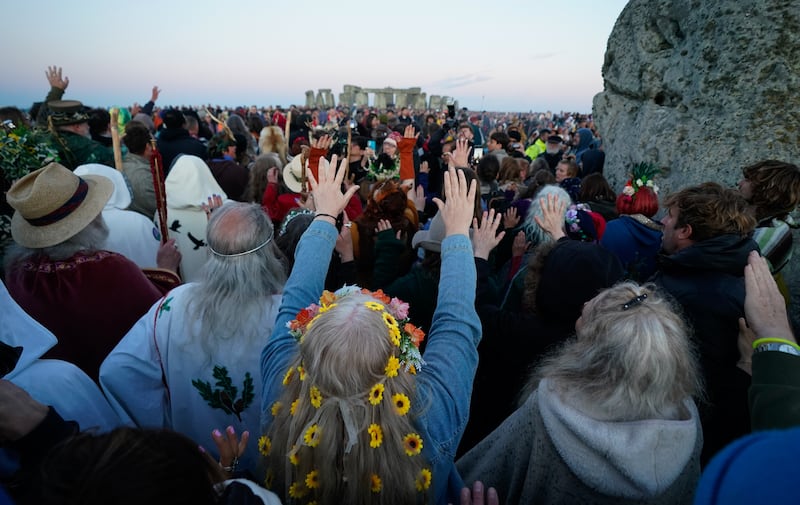 People gather around the Heel Stone ahead of sunrise as they take part in the summer solstice at Stonehenge