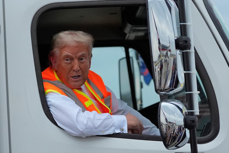 Donald Trump talks to reporters as he sits in a garbage truck (Julia Demaree Nikhinson/AP)