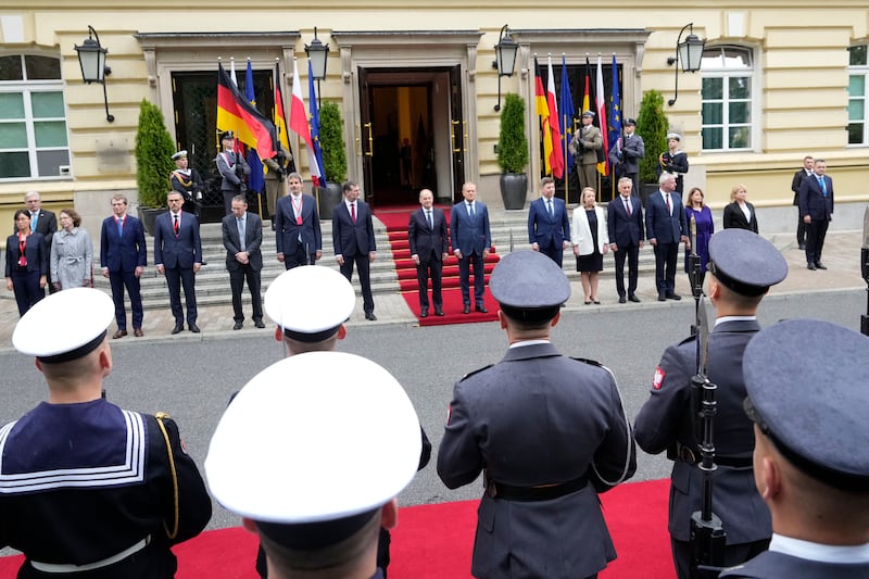 German Chancellor Olaf Scholz, centre left, and Polish Prime Minister Donald Tusk, centre right, review the guard of honour in Warsaw (Czarek Sokolowski/AP)