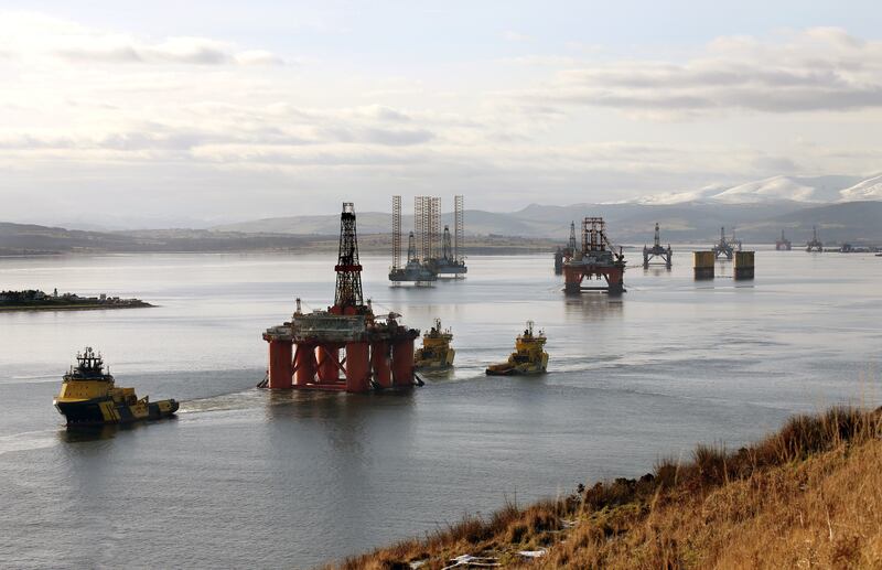 An oil platform is moved with tug boats amongst other rigs which have been left in the Cromarty Firth near Invergordon in the Highlands of Scotland