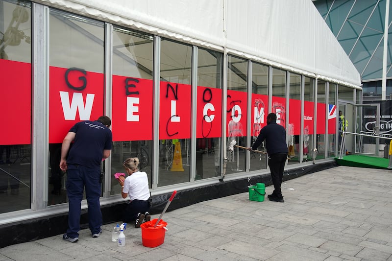 People remove graffiti sprayed by Youth Demand on the security check-in building